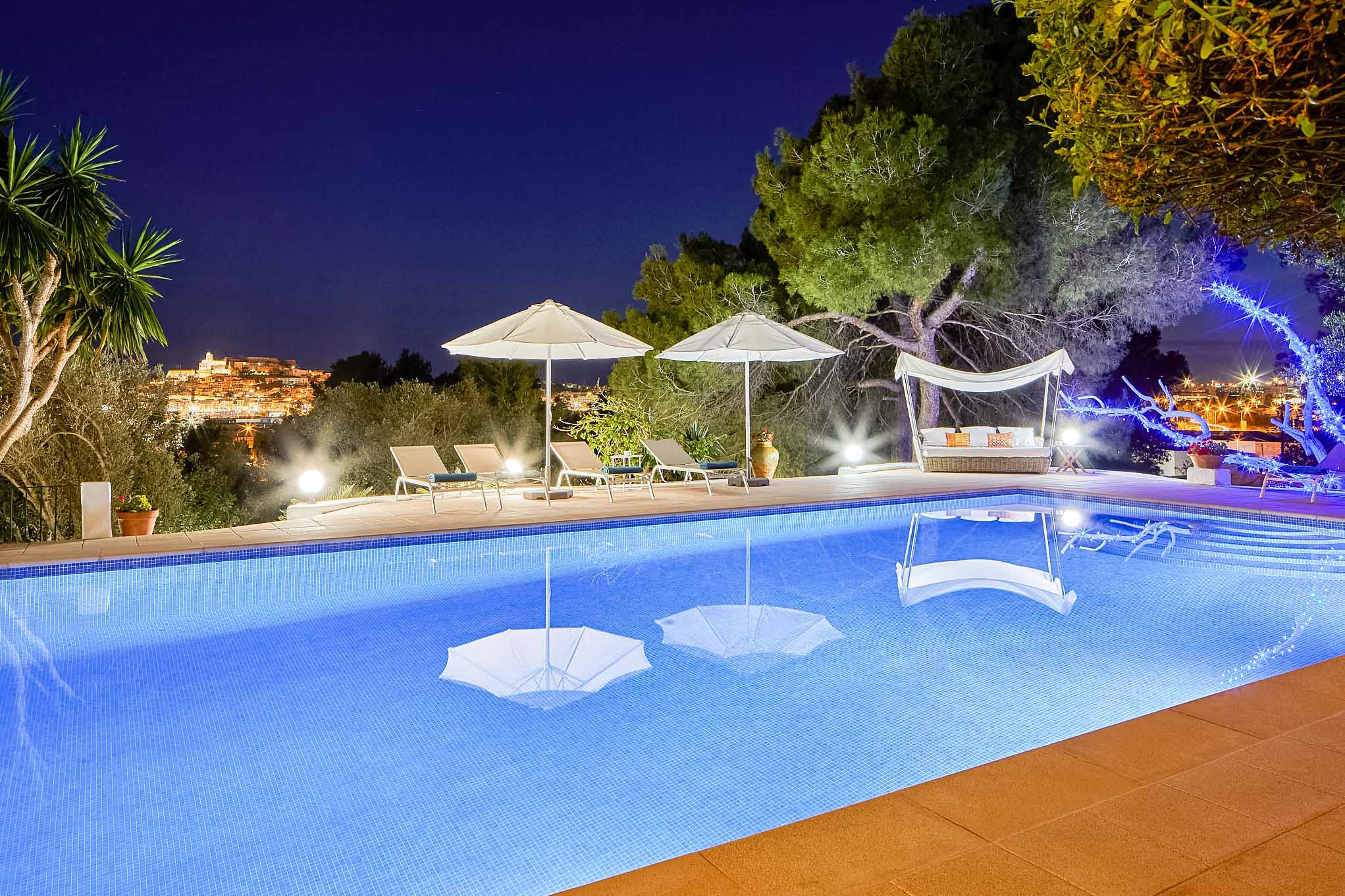 Vue sur la piscine illuminée la nuit à la Villa Elba