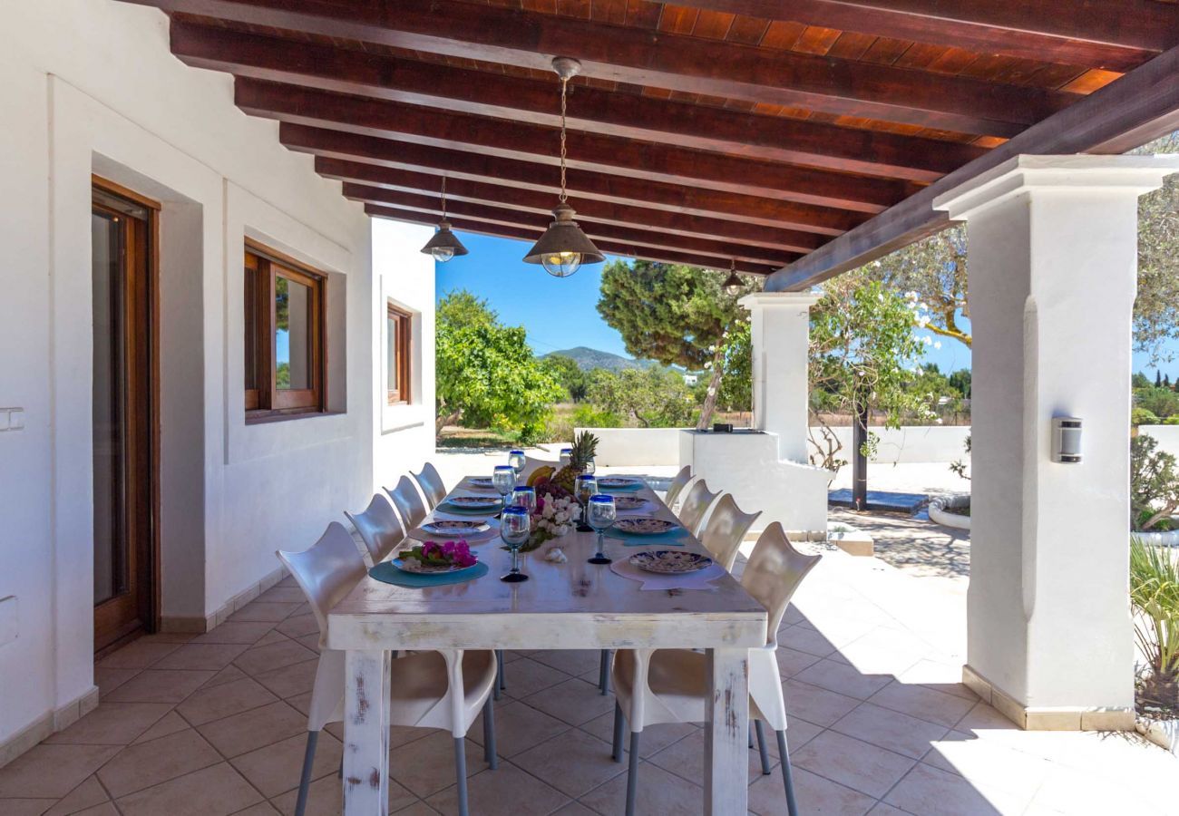 Covered terrace with tables and chairs for the 10 guests of the gîte.