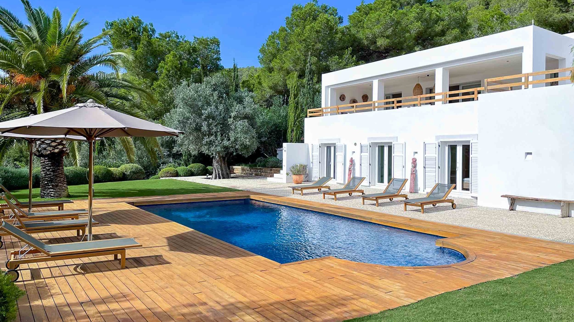 Piscina climatizada rodeada de tarima exótica y palmeras