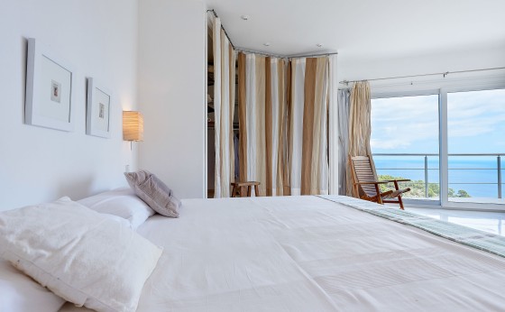 Dormitorio elegante con vistas al mar y baño en suite